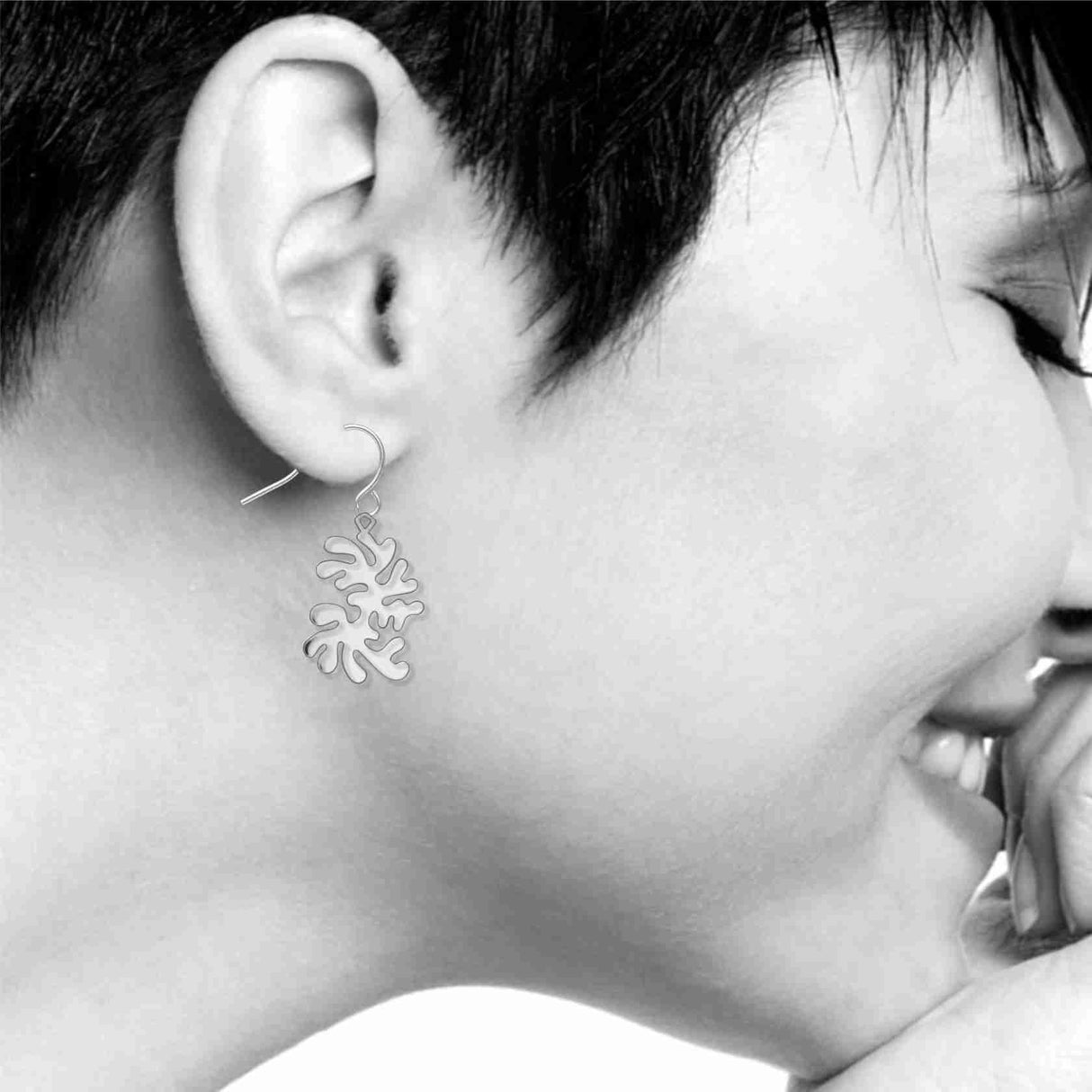 Model wearing Ocean Life dangling earrings featuring abstract silver-tone coral-inspired shapes suspended from fishhook ear wires.