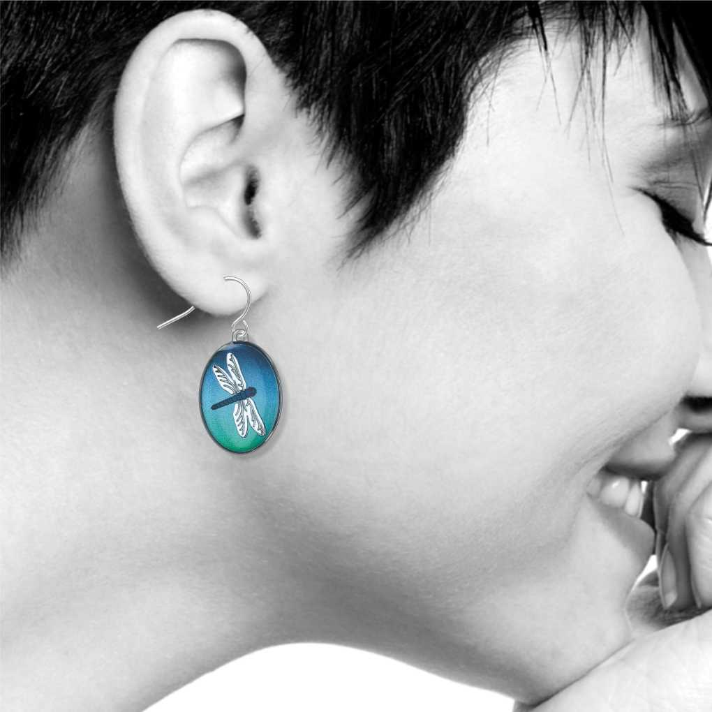 Dragonfly earrings: oval blue and green dragonfly drop earring worn on ear.