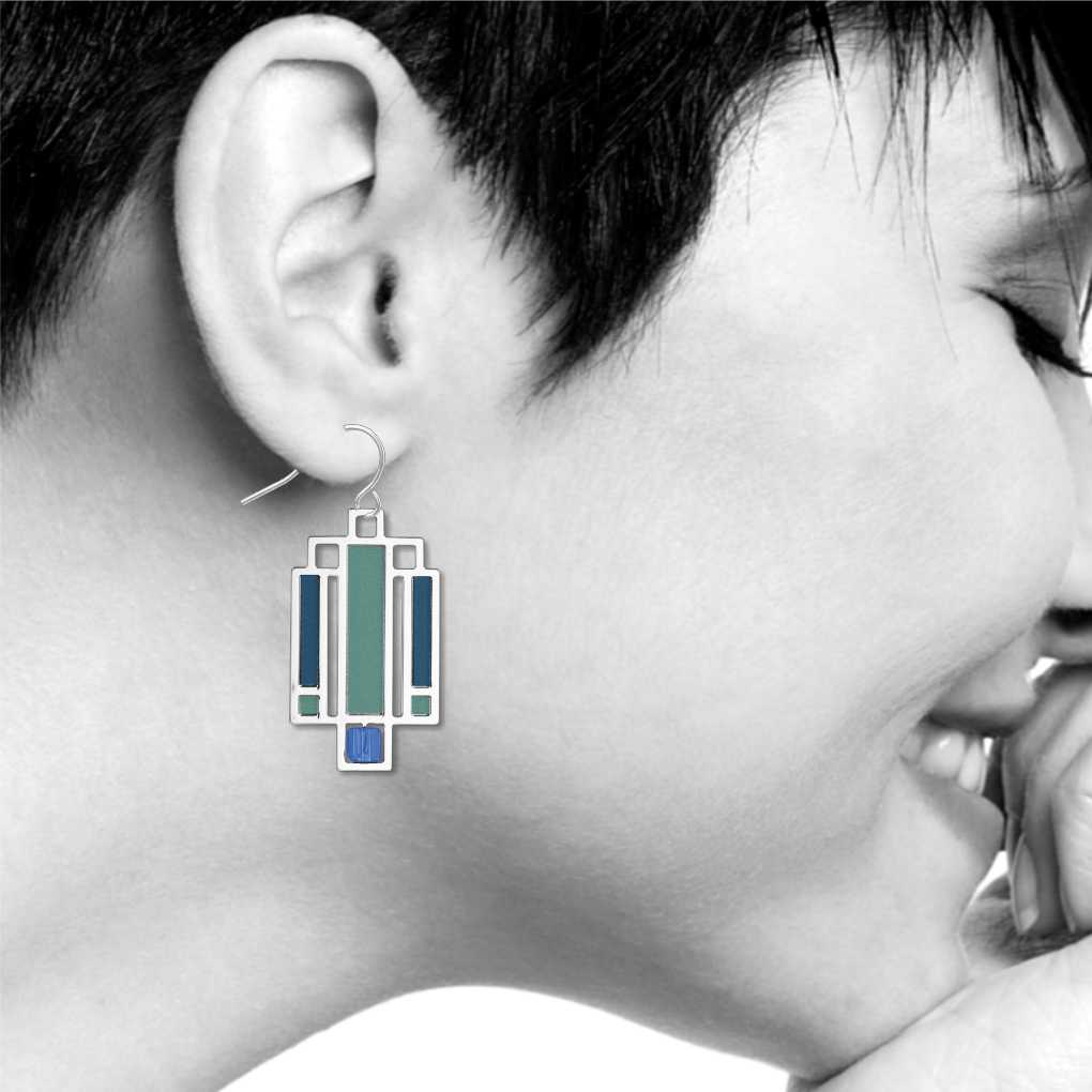 Willits Lightscreen Earrings: silver-tone geometric earring inspired by Frank Lloyd Wright's Willits House lightscreen design, featuring teal, turquoise, and cobalt blue stained-glass-style accents shown on model