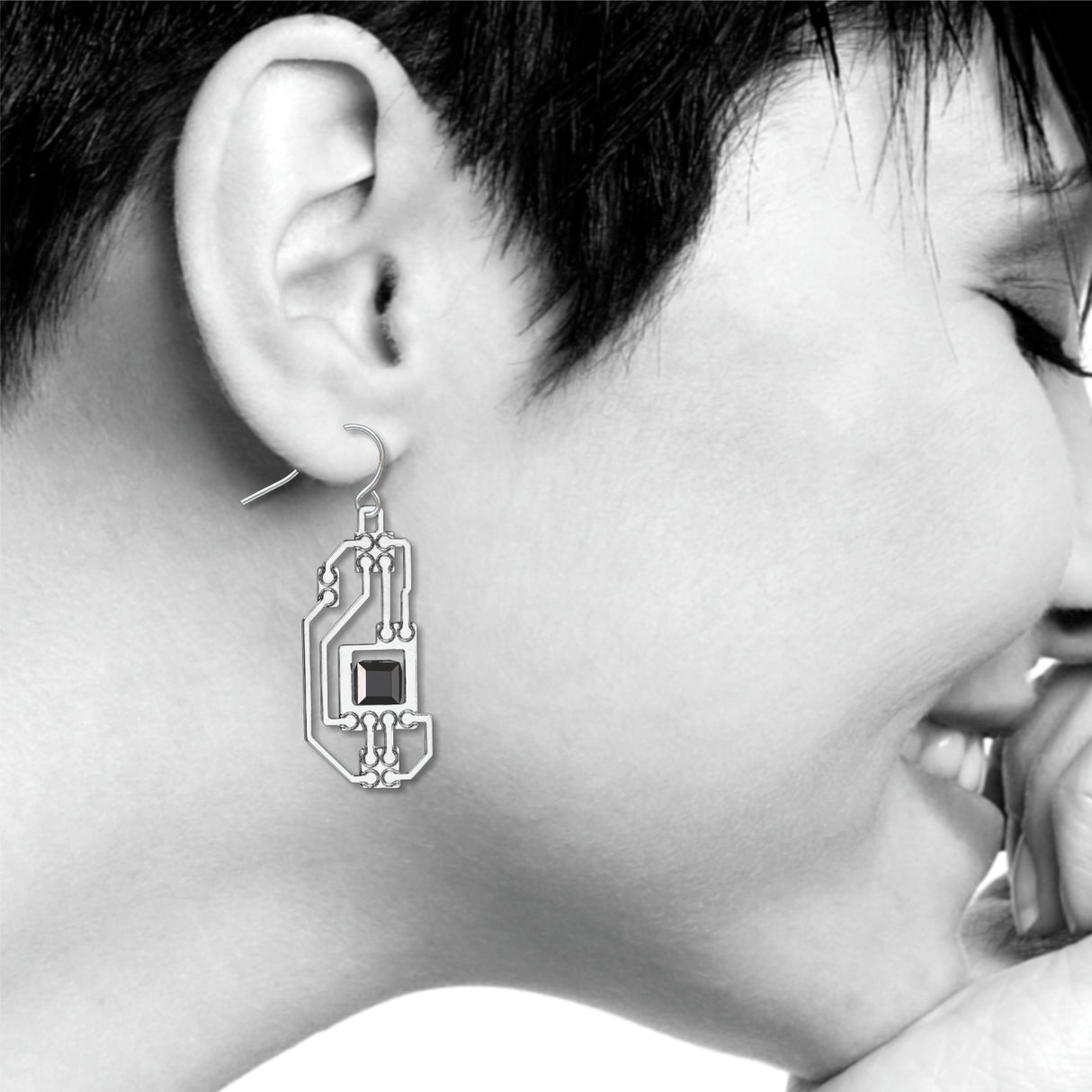 Circuits abstract silver drop earring worn on ear with intricate circuit board-inspired detailing and a faceted black geometric accent in a modern industrial design