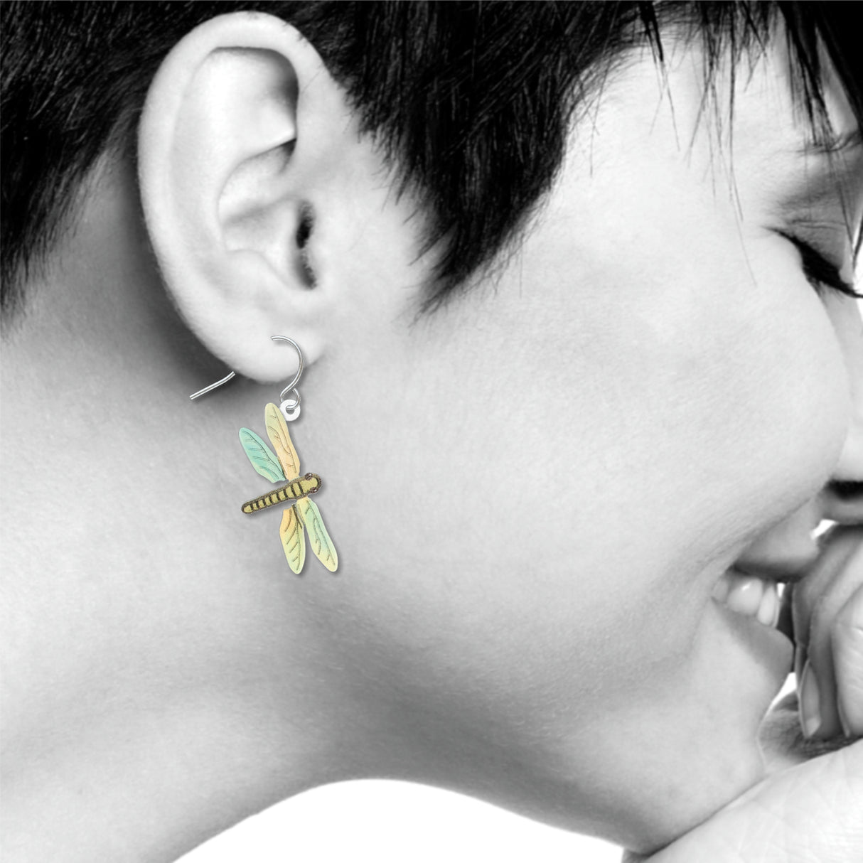 Dragonfly earrings: pastel yellow, green, and blue dragonfly drop earring worn on ear.