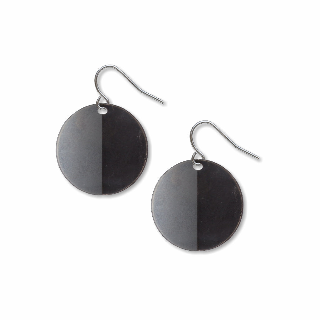 An Orb circular drop earrings with a bold split-tone black and gray finish, inspired by Ellsworth Kelly’s minimalist sculptural artwork and modern geometric forms
