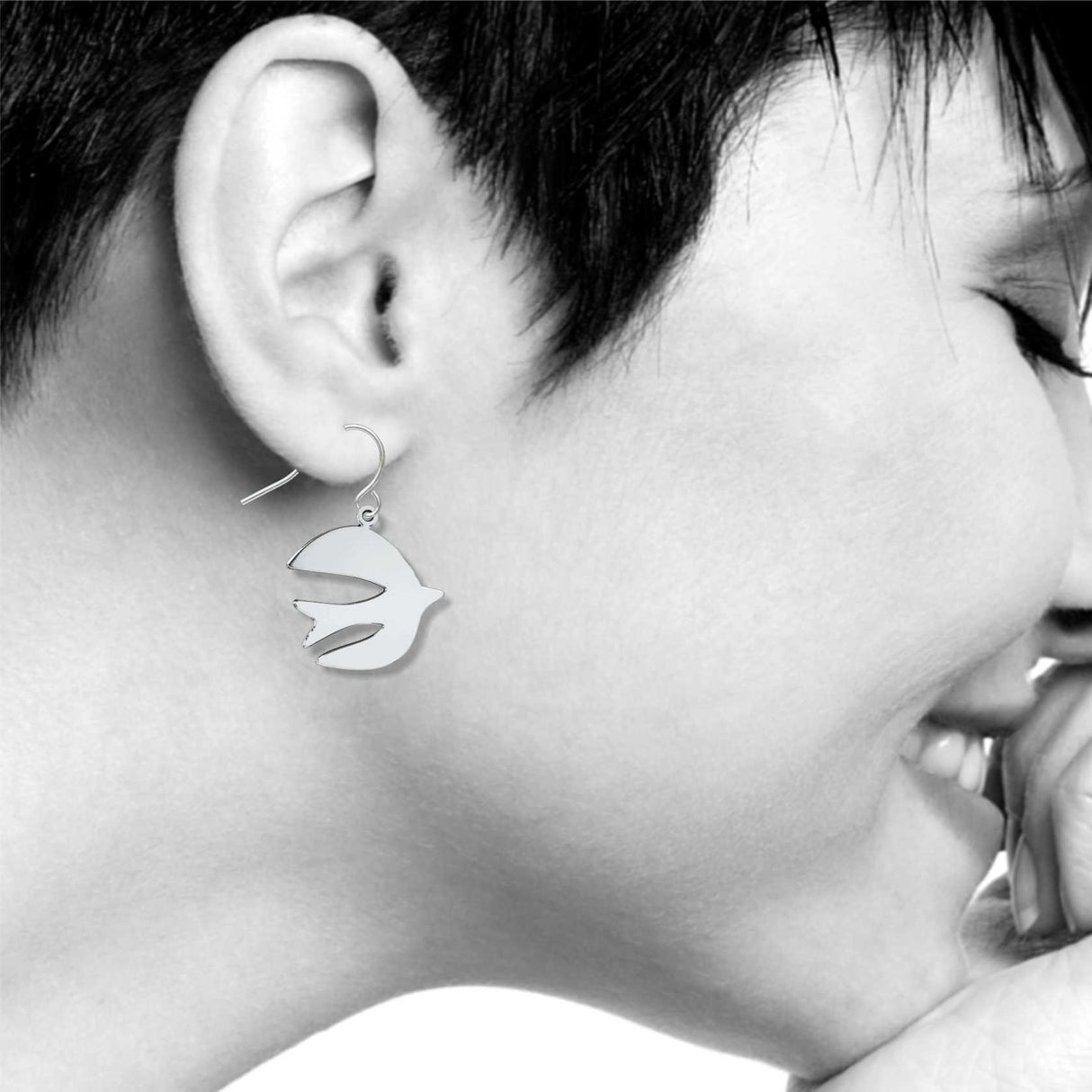 Model wearing After Matisse A Bird silver-tone dangle earrings featuring abstract bird silhouettes inspired by Matisse paper cutout artwork.
