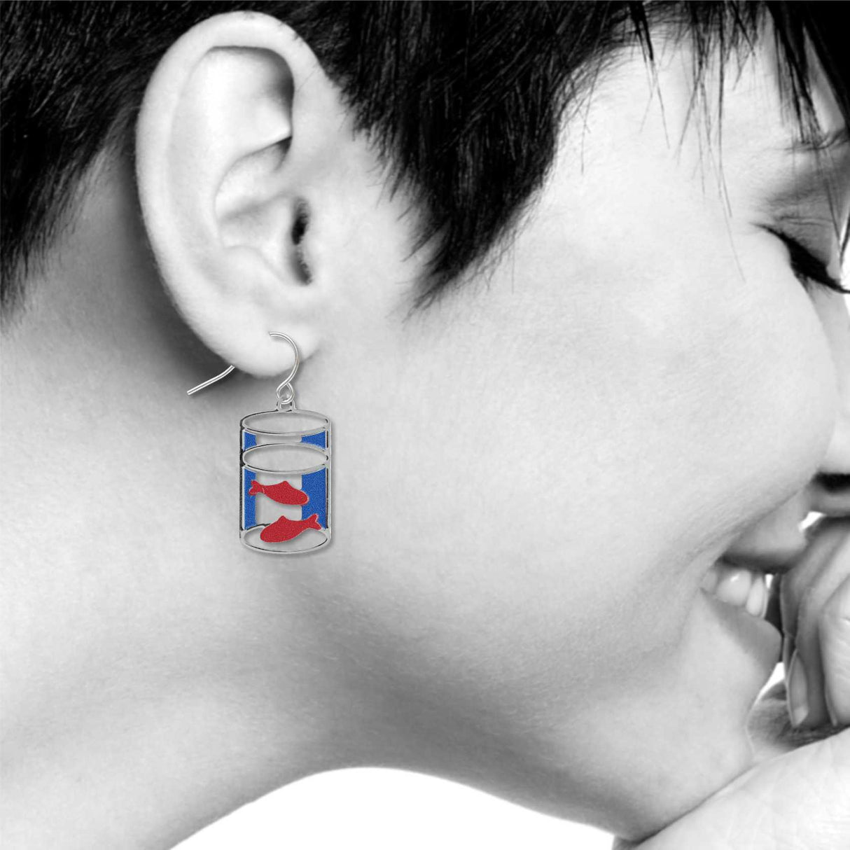 Model wearing goldfish drop earring featuring red fish inside a silver cylindrical bowl design with blue enamel accents.