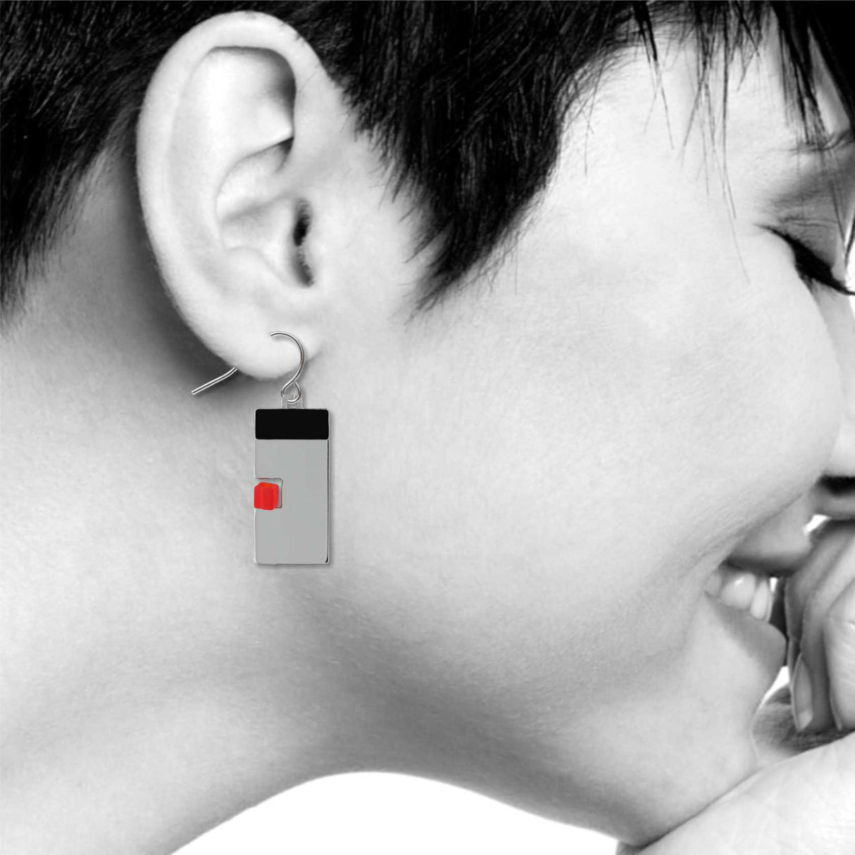 Model wearing balance earring featuring a geometric silver rectangle with a black top and red accent block.