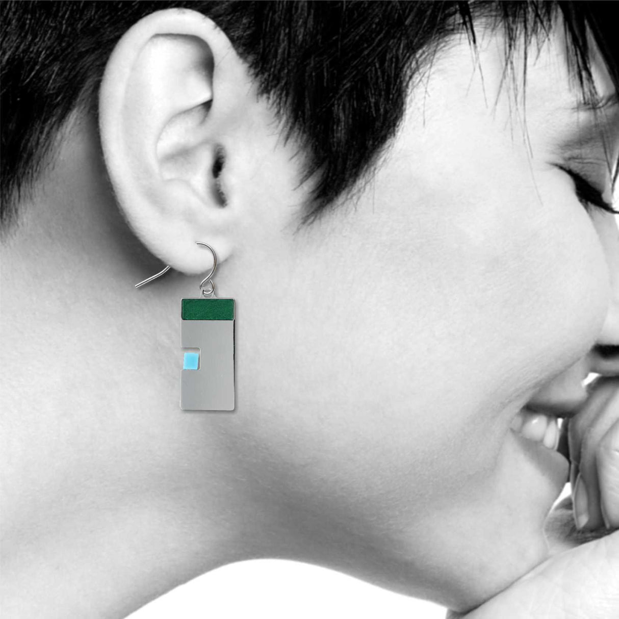 Model wearing Harmony geometric drop earring, featuring a silver rectangular design with a deep green top bar and a soft blue accent, styled in a clean, modern look.