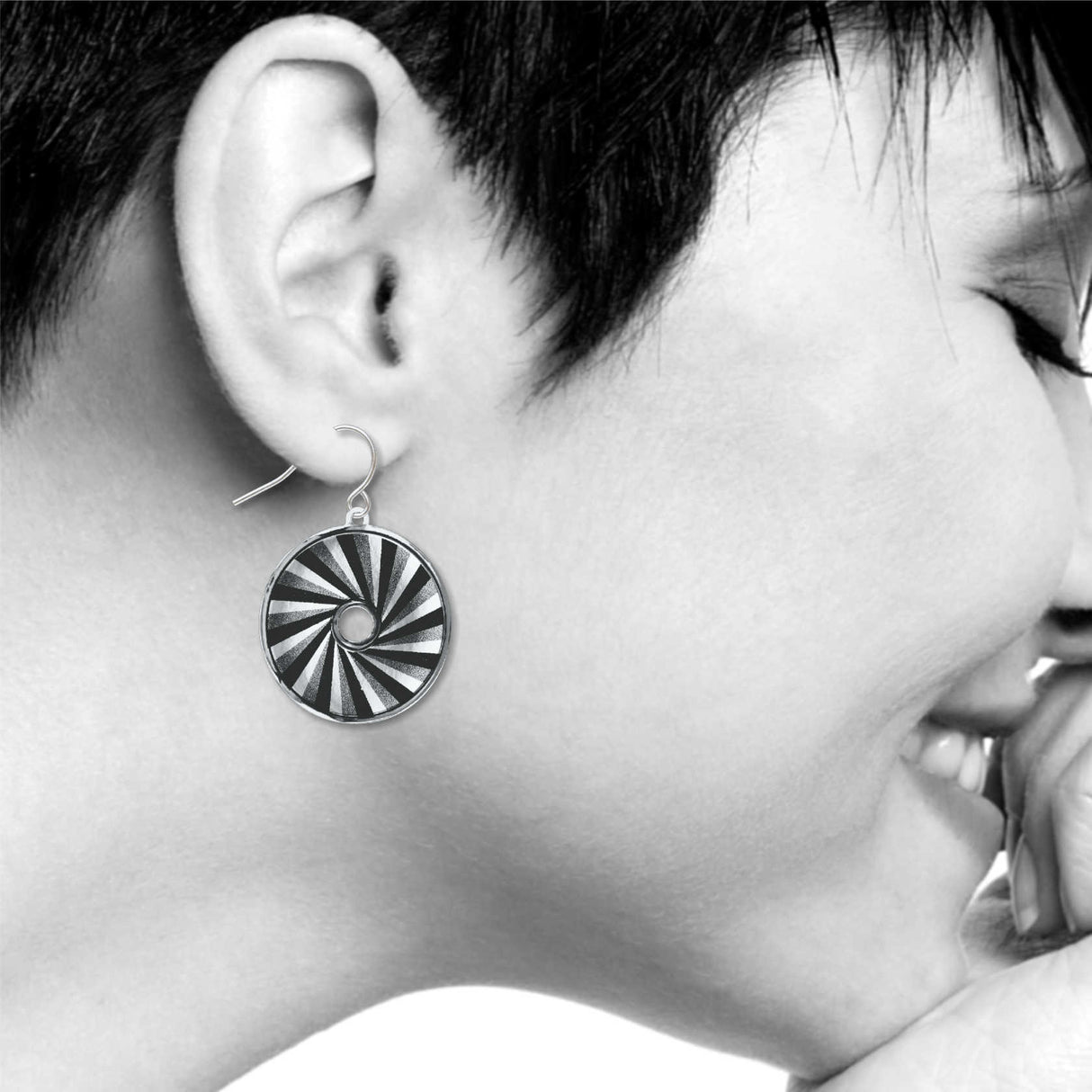 Raven Black earrings: black, silver, and white spiral circle drop earring inspired by automotive tail light design on model
