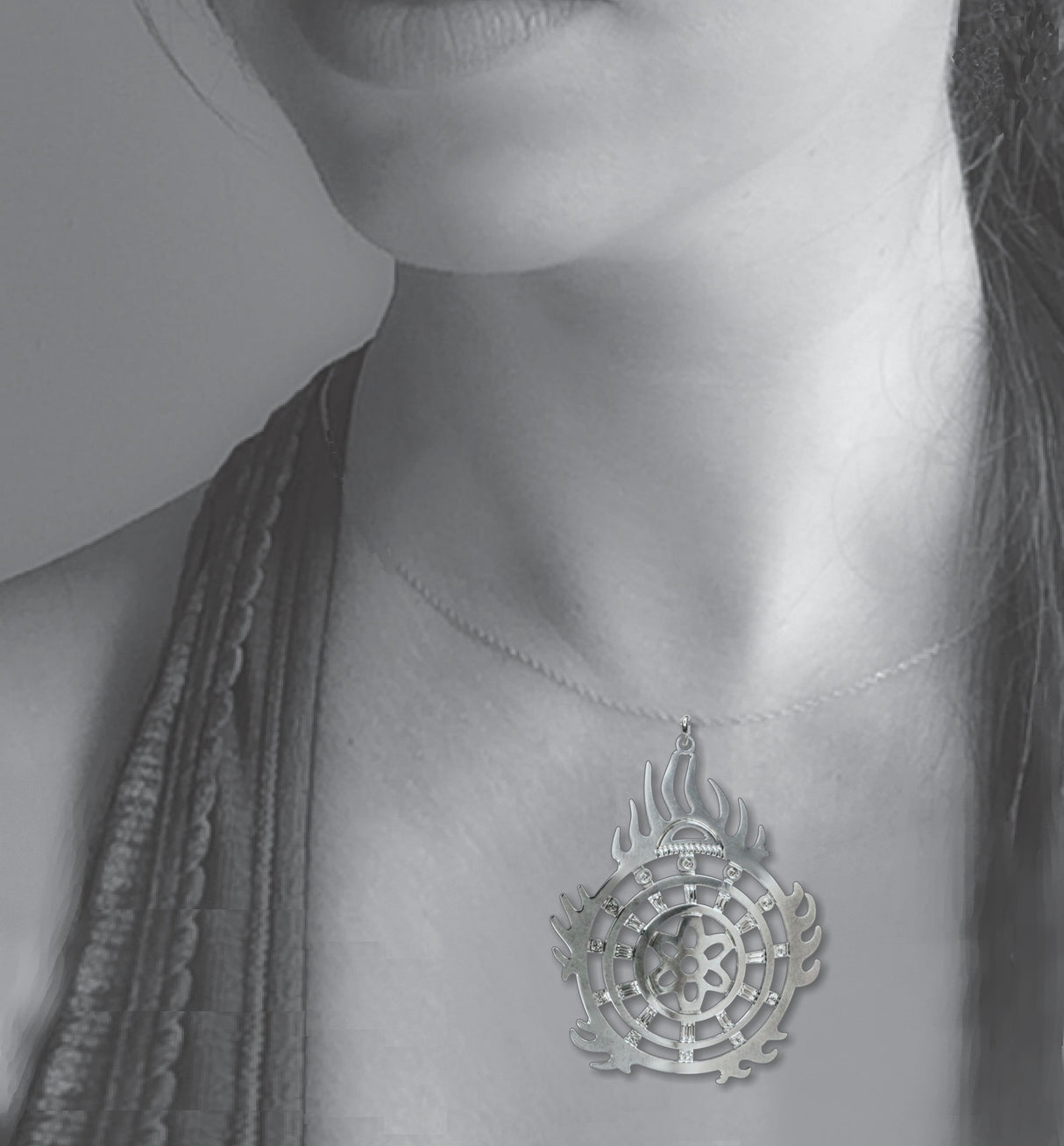 Halo of Flames Necklace worn on a silver chain, featuring a circular silver pendant with flame-like edges, geometric cutouts, and crystal accents displayed against the neckline of a model.