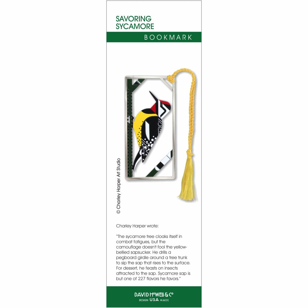 A metal Charley Harper bookmark featuring an illustration of a bird with a yellow-bellied sapsucker on a sycamore tree in a silver frame attached to a golden tassel.