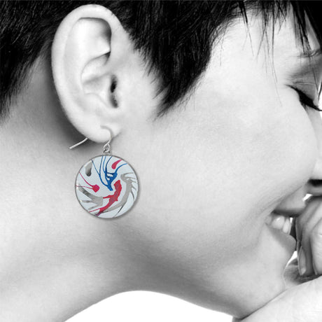 Model wearing Spin Art drop earring, featuring a circular design with abstract swirls of red, blue, and gray, creating a bold, modern artistic look.