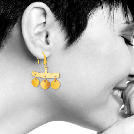 Close-up of a person wearing gold earrings with dangling circles.