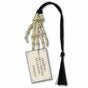 A metal bookmark in the shape of a skeleton hand with a attached card reading 'ARRET! CE LA VIVRE EST LA REINE DE LA MORT.' Adorned with a black braided tassel.