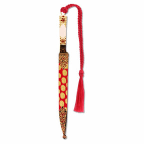 A decorative metal bookmark designed to resemble a Mughal dagger with a gold finish, floral patterns, and a red tassel.
